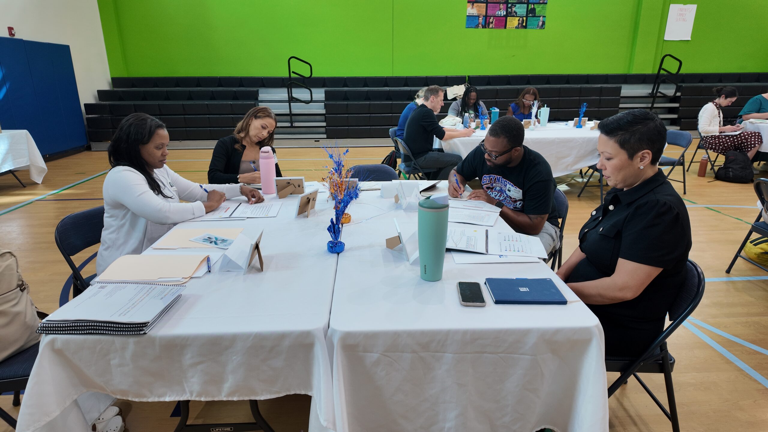 Four educators read session materials and record their thinking around a table at Two Rivers.
